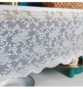 Close-up of white lace table runner with elegant rose patterns and scalloped edge