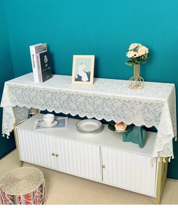 Detail view of white lace table runner with floral embroidery and tassel fringe