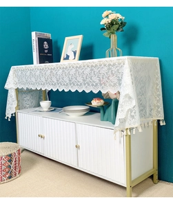 Detail of white lace table runner featuring floral hollow patterns and soft pom-pom fringe