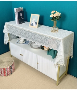 Close-up of white lace table runner featuring crochet floral patterns and fringe details