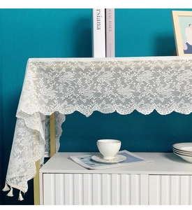 Close-up of white floral lace table runner with elegant tassels on a modern cabinet