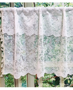 Macro shot of white lace kitchen curtain with floral patterns and hanging tassel trim