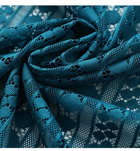 Detaillierte Nahaufnahme von pfauenblauem Spitzenstoff mit feinem floralem Lochmuster