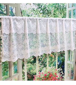 Detail of white lace kitchen cafe curtain with floral crochet pattern and tassel fringe
