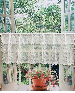 Close-up of white floral lace cafe curtain with delicate pom-pom tassel fringe trim