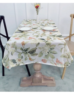 Detail view of rustic floral linen tablecloth featuring green leaves and orange flowers