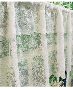 Close-up of white lace cafe curtain with intricate floral patterns and rod pocket design