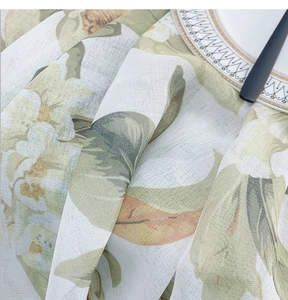 Close-up of linen-textured floral tablecloth showing soft folds and leaf print detail
