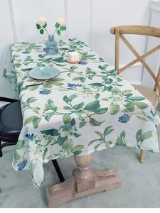 Detailed close-up of pastoral linen tablecloth with green leaves and blue berry prints