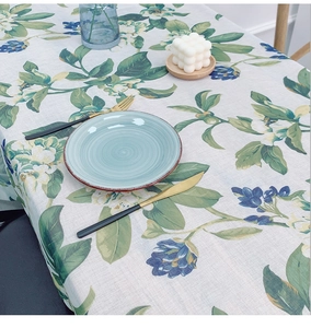 Detail of floral printed linen tablecloth with rustic leaves and blue flowers on a table