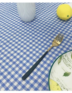 Close-up of elegant black and gold stainless steel fork on blue checkered tablecloth