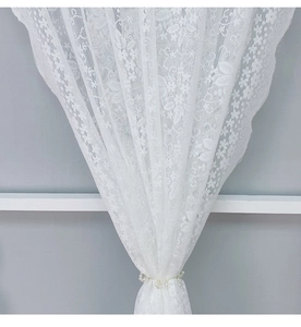 Detail von weißer Spitzenvorhang mit Blumenmuster und eleganter Perlen-Raffhalterung
