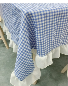 Close-up of blue and white gingham tablecloth with decorative white ruffled lace edge