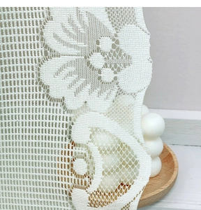 Close-up of white lace roman blind showing intricate floral embroidery and wavy edges