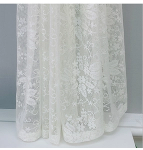 Detailaufnahme von weißem Spitzenvorhang mit zarten floralen Stickereien und Mustern