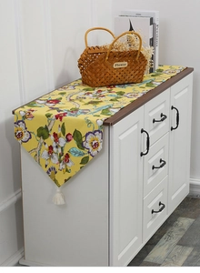 Detail of yellow floral table runner with colorful flowers and cream tassels on edges