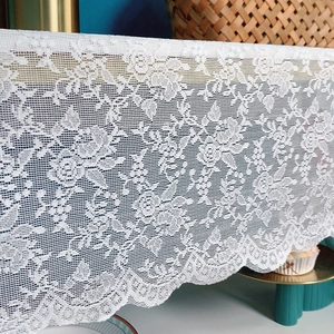 White lace table runner with elegant rose floral patterns and wavy scalloped edges