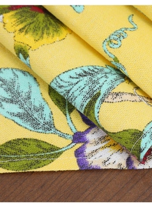 Detail of yellow bamboo cotton table runner with floral print on a dark wood surface