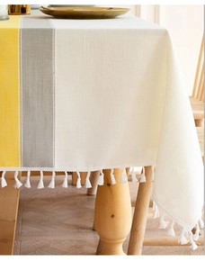 Close-up of yellow and gray striped linen tablecloth with white decorative cotton tassels