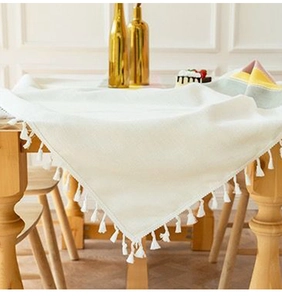 Close-up of minimalist white cotton linen tablecloth with detailed fringe tassels