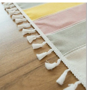 Close-up of striped cotton linen tablecloth featuring decorative white cotton tassels
