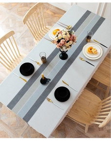 Detail of grey striped cotton linen tablecloth with white decorative fringe edges