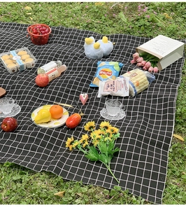 Classic black and white checkered picnic mat spread on green grass for outdoor dining