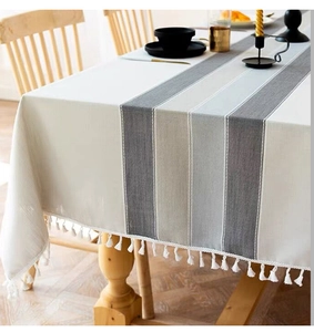 Detail of Nordic striped cotton linen tablecloth with elegant white pom-pom fringe