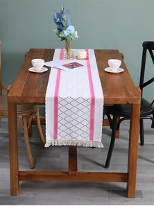 Macro shot of Nordic style table runner featuring grey diamonds and pink stripes with tassels