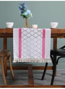 Detail of bohemian table runner with pink hollow lace patterns and fringe edge