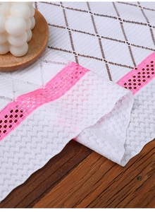 Detail showing white crochet table runner with pink lace edges and geometric mesh patterns