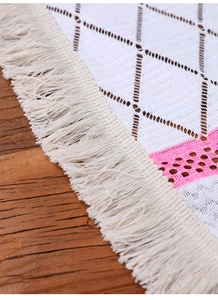 Close-up of bohemian table runner with white diamond weave and long fringe tassels