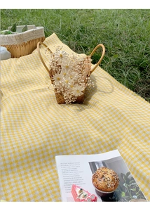 Close-up of yellow and white checkered picnic mat texture on green grass lawn