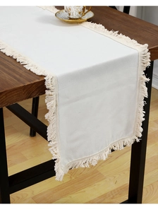Gros plan sur le chemin de table en lin de coton blanc avec d'élégants détails de franges