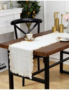 Détail d'un chemin de table en lin blanc avec des franges à pompons de style bohème