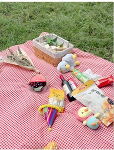 Classic red and white checkered picnic mat set with basket on a lush green lawn