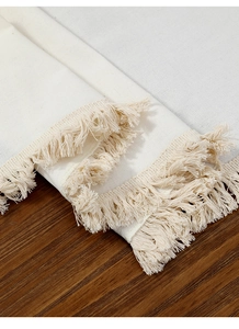 Gros plan d'un chemin de table blanc tissé avec glands sur une table en bois