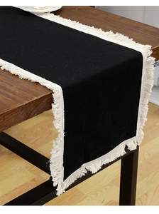 Détail d'un chemin de table noir en coton et lin avec de fines franges blanches