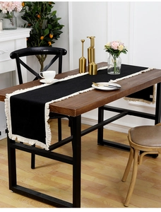 Détail du chemin de table en coton lin noir avec franges blanches sur table en bois