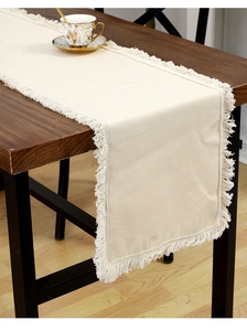 Texture détaillée du chemin de table en lin beige avec élégantes franges longues