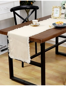 Gros plan du chemin de table beige avec franges décoratives sur une table en bois foncé
