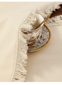 Détail d'un chemin de table en coton et lin crème avec des franges élégantes et du tissu texturé