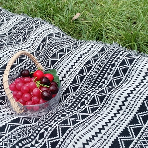 Portable Bohemian picnic mat with black and white geometric patterns and tassel edges