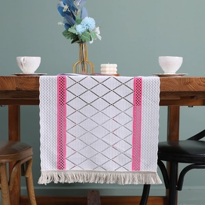 Nordic vintage lace table runner with hollow design and fringe tassels on wooden table