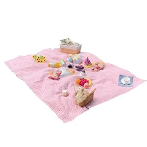 Pink and white checkered outdoor picnic mat with decorative baskets and snacks