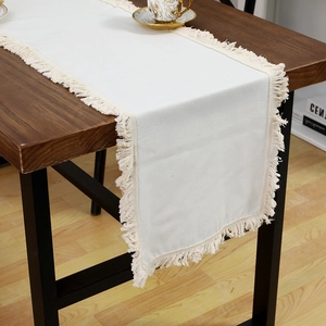Chemin de table élégant en lin blanc avec franges sur une table en bois pour salle à manger