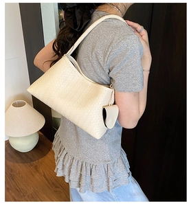 Close-up of cream woven shoulder bag featuring textured synthetic leather and mini pouch
