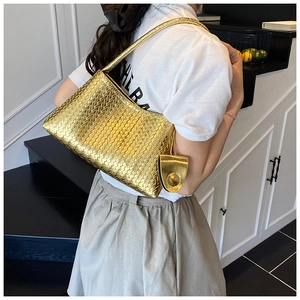 Close-up of golden woven tote bag with matching pouch shown on shoulder from side view