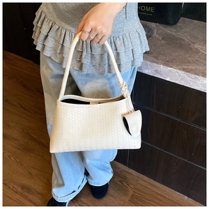 Detailed view of cream woven underarm bag texture with matching mini coin purse