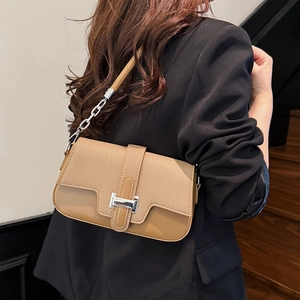 Chic khaki textured crossbody bag with silver H-buckle worn by a model in black suit